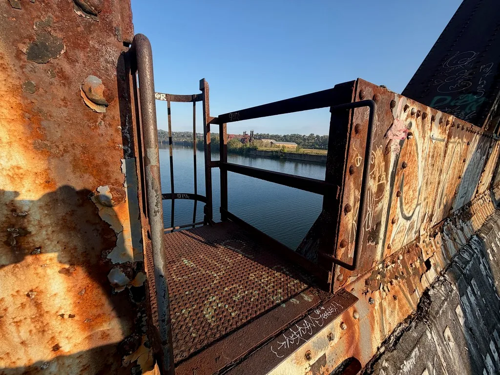 Rusty walkway and metal plates of an old bridge above water.