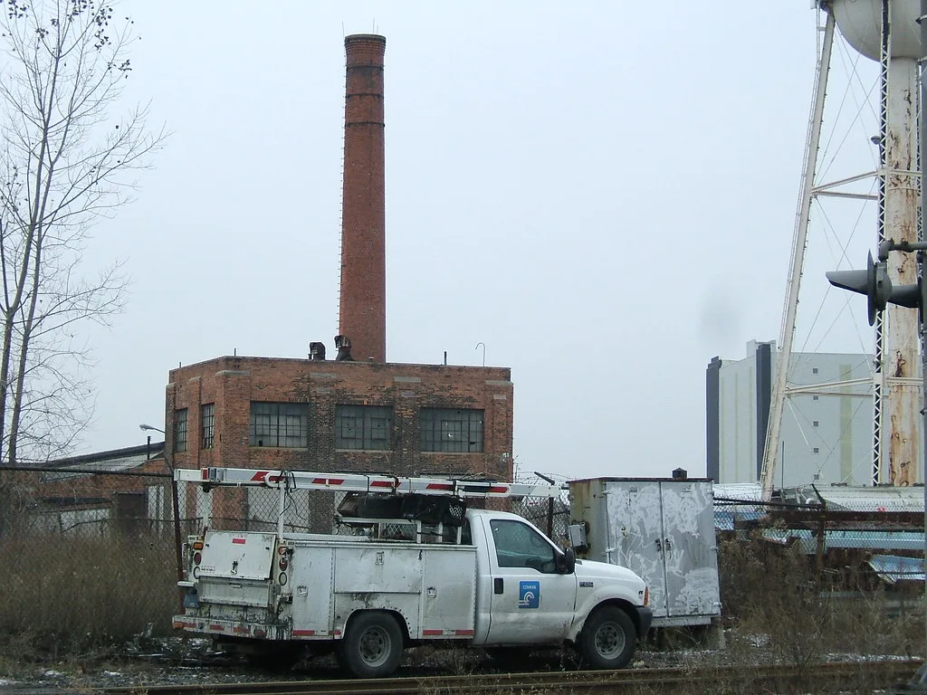 Old brick industrial building with a chimney behind a utility vehicle.