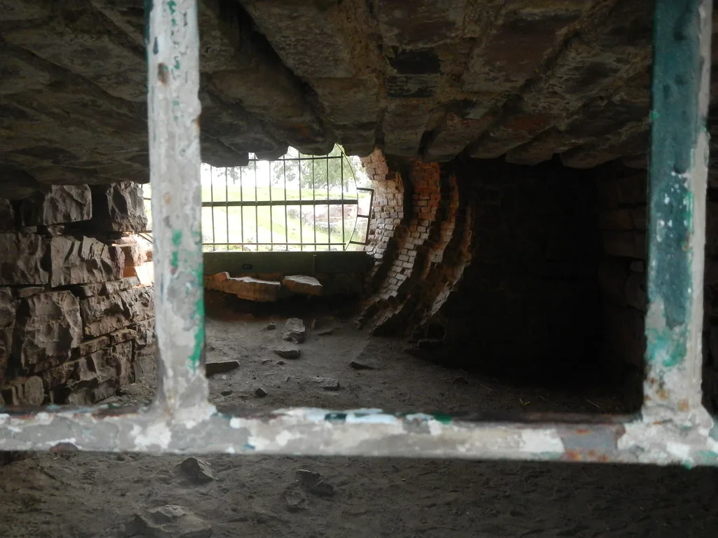 Vaulted stone and brick interior seen through an unglazed window.