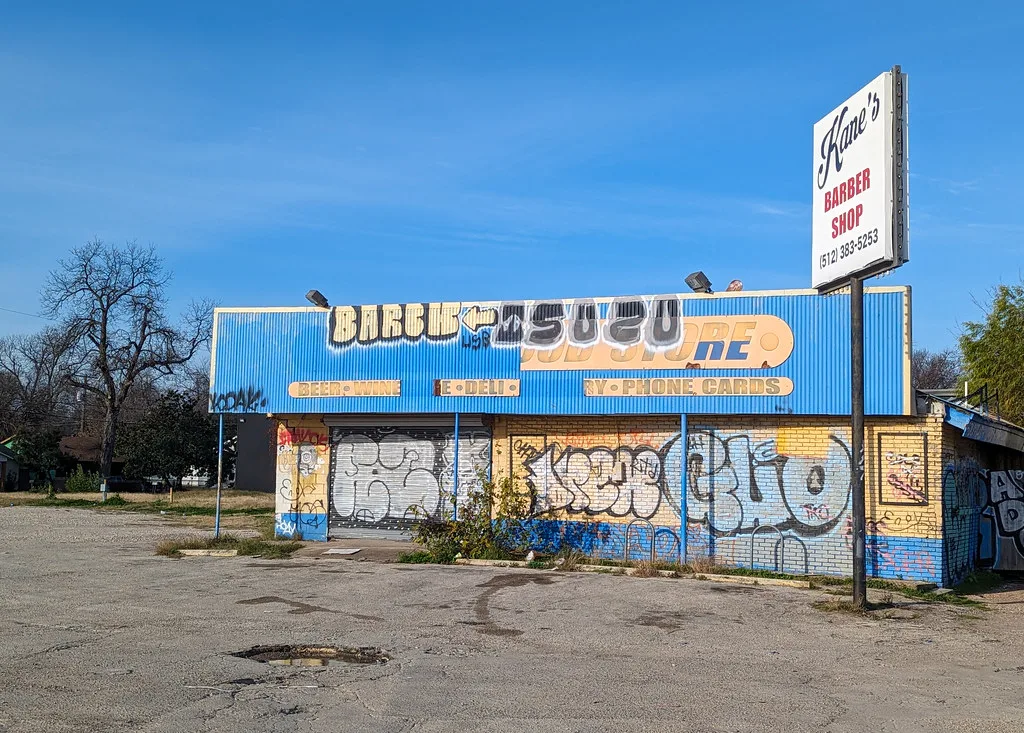 Former blue shop with graffiti-covered closed shutters.