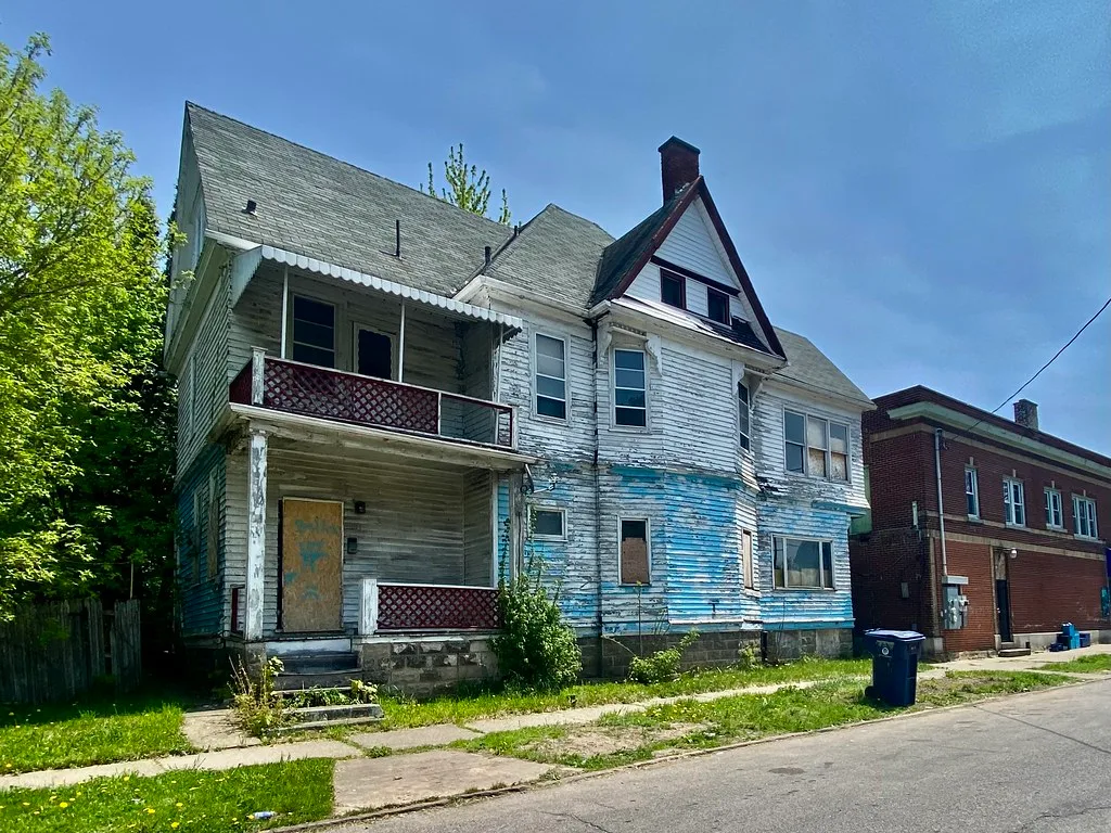 Old house with peeling siding and boarded openings.