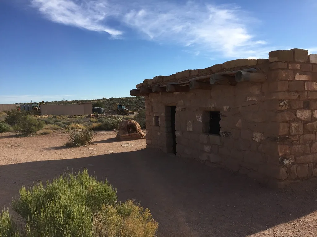 Small stone building with empty openings in an arid landscape.