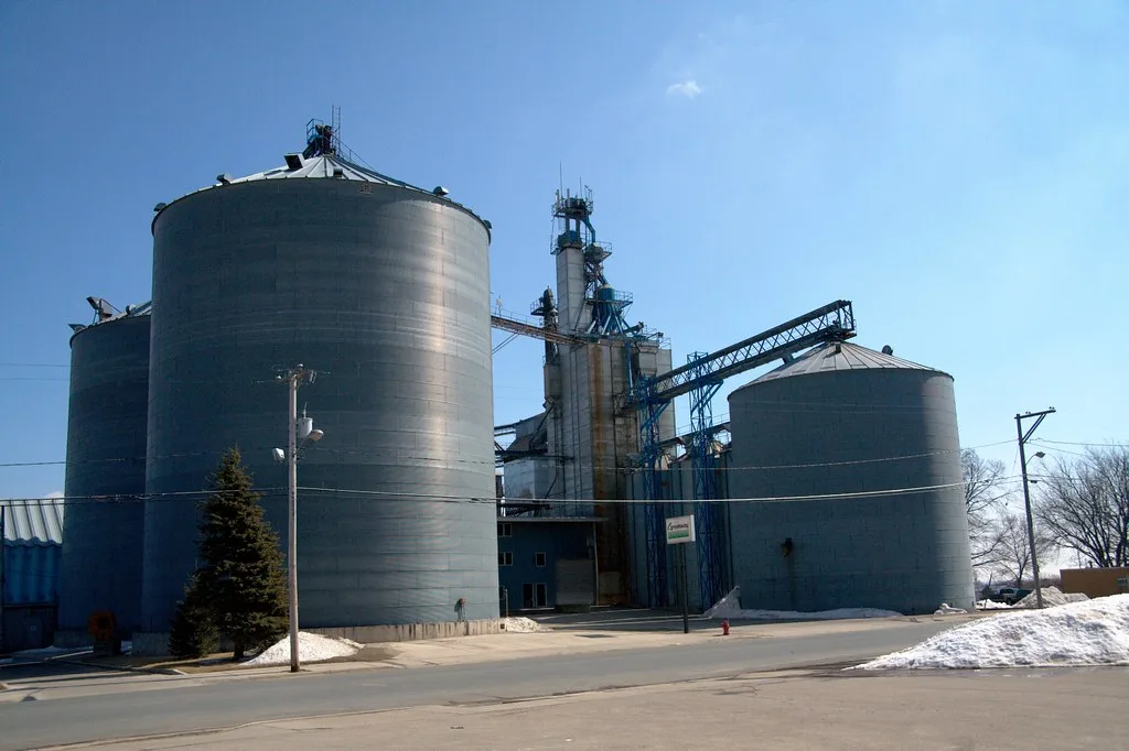 Metal silos and tower of a grain elevator in winter.