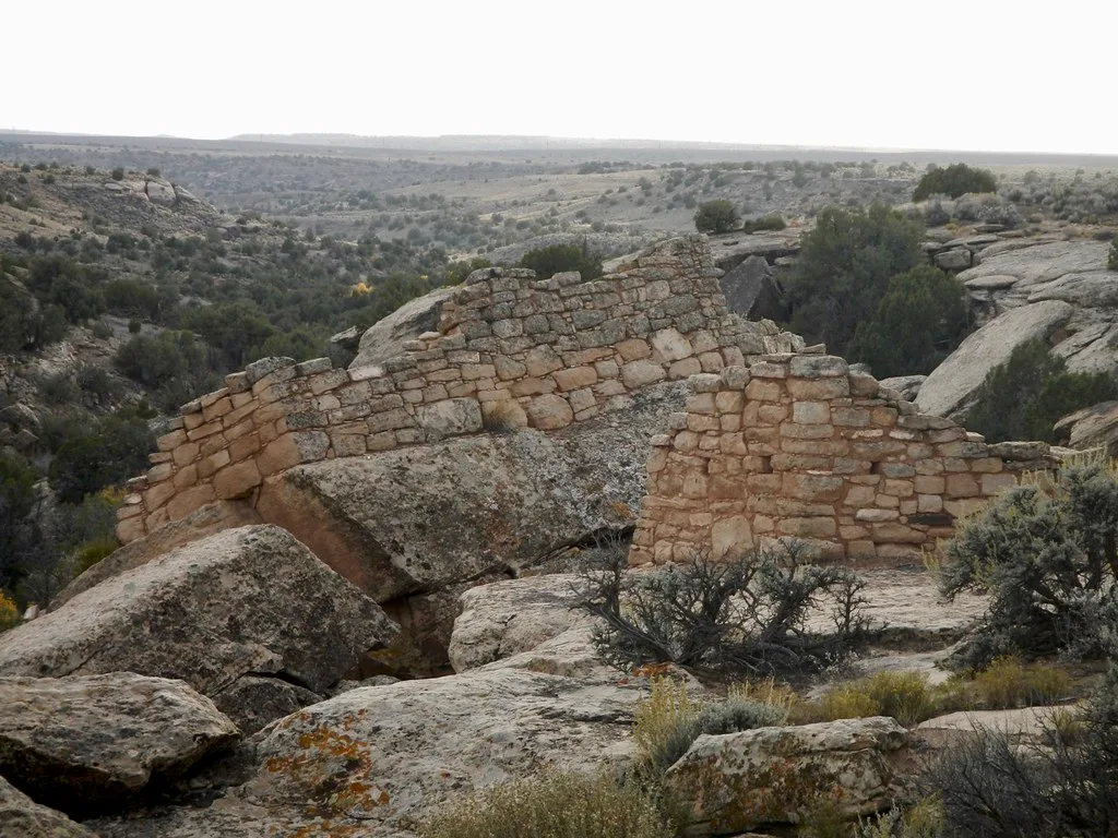 Ruines de murs de pierre sur de grands rochers dans un paysage sec.