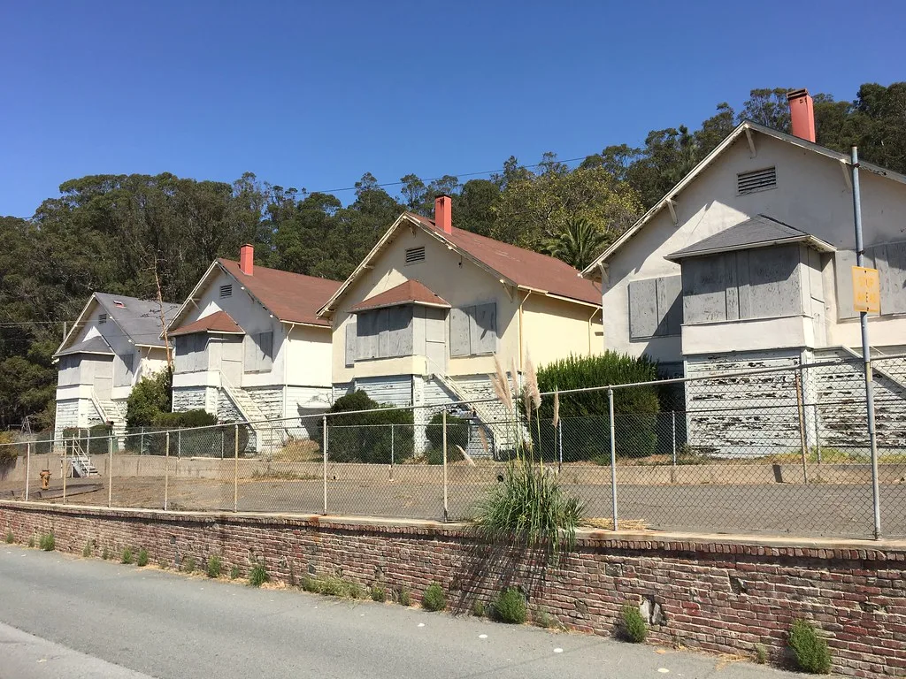 Row of boarded houses behind a fence.