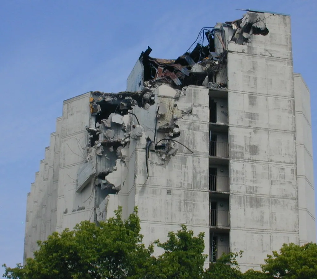 Partly demolished concrete building with torn-open upper floors.