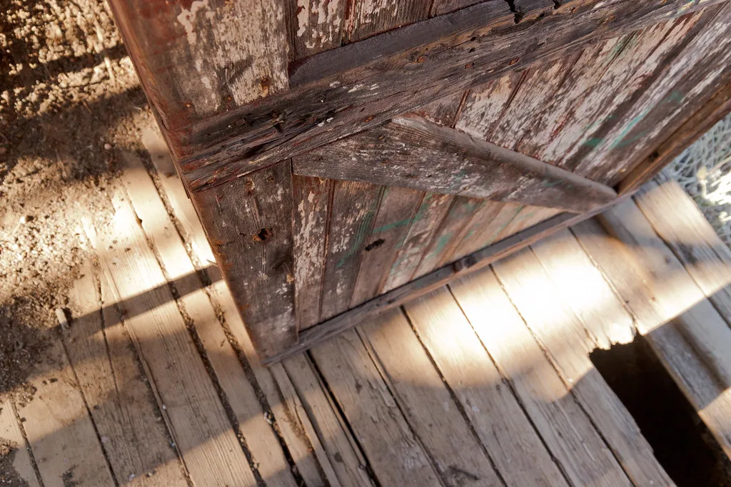 Dilapidated wooden door above a floor with missing boards.