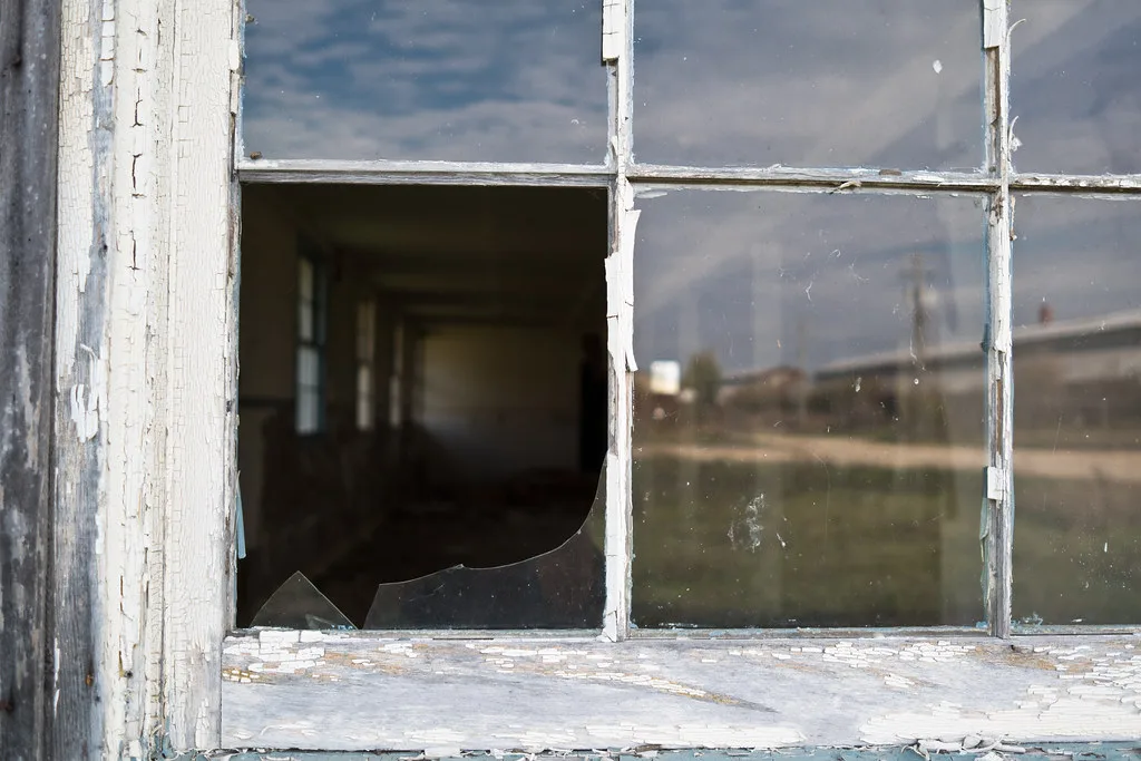 Old window with a broken pane and peeling paint.