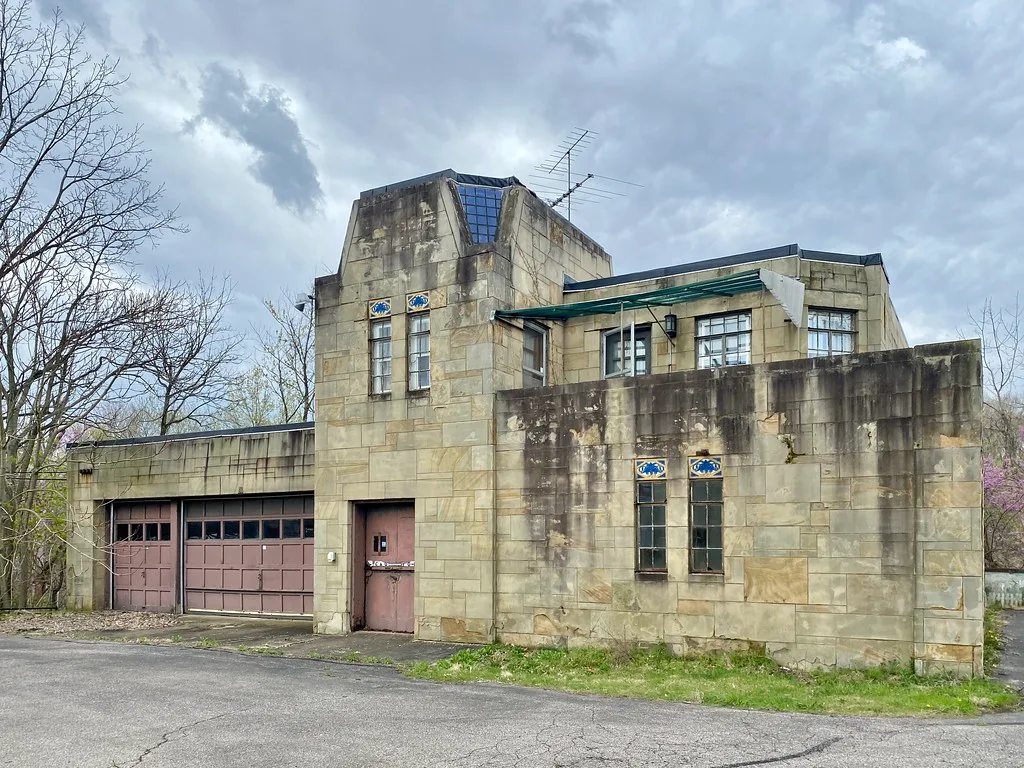 Old stone garage with a boarded and deteriorated frontage.