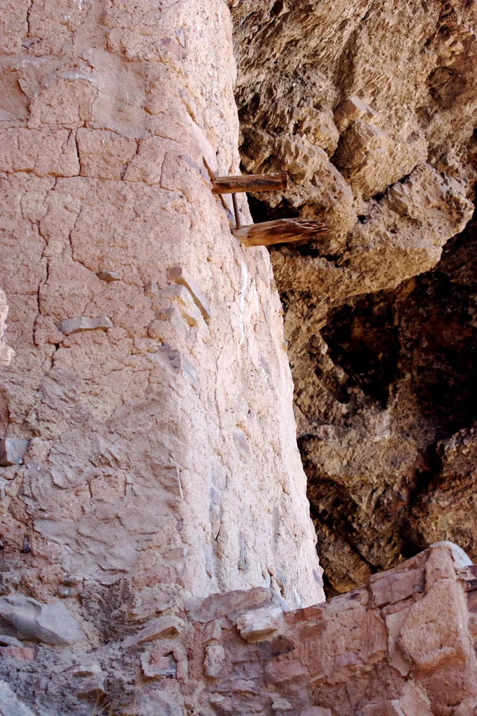 Old masonry wall with beam remnants beneath a rocky overhang.