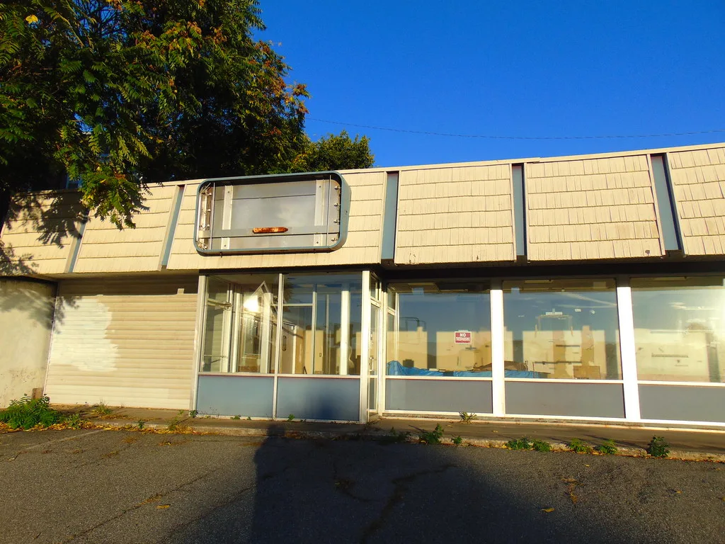Old commercial unit with an empty sign frame and neglected display windows.