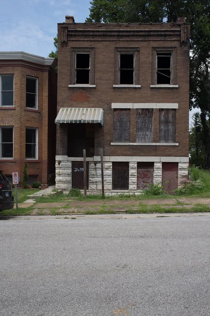 Brick house with empty and boarded windows.