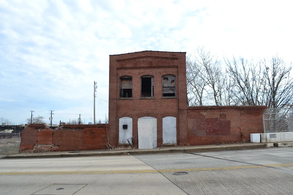 Old narrow brick building between partly collapsed walls.