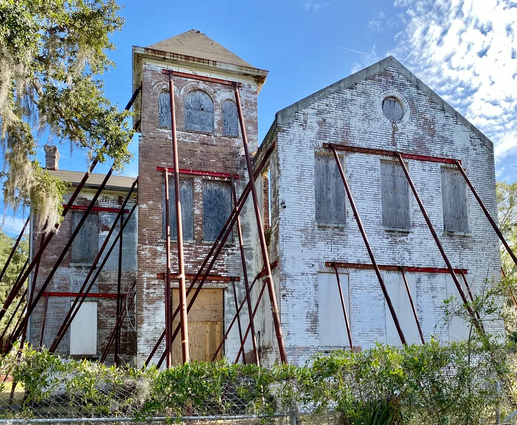 Ancien bâtiment de briques condamné et soutenu par des étais métalliques.