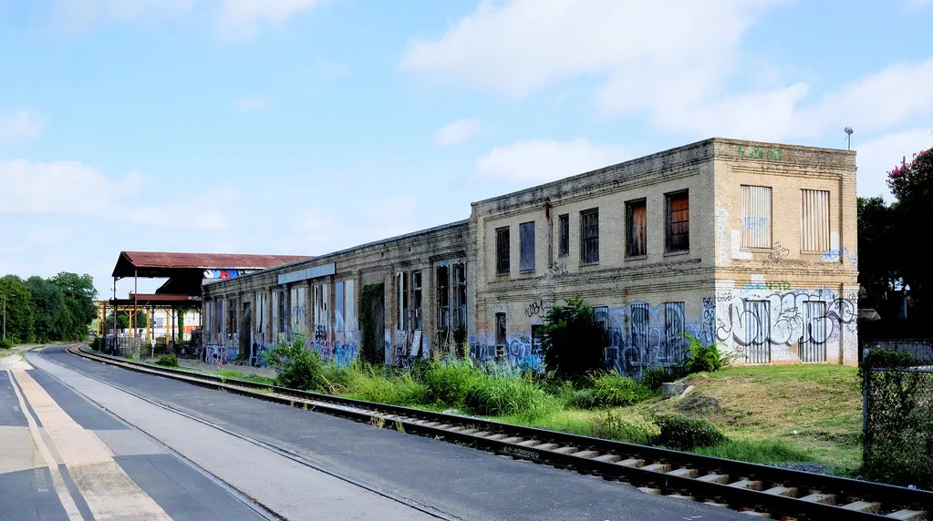 Abandoned industrial building covered in graffiti beside railway tracks.