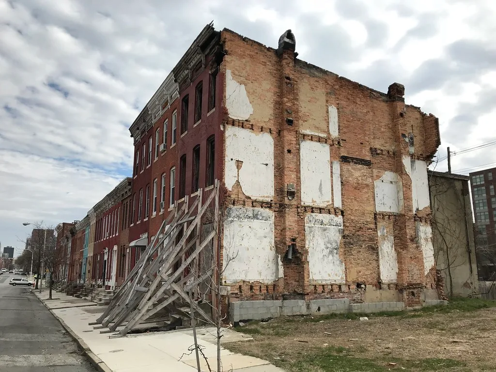 Deteriorated old brick building supported by large wooden braces.