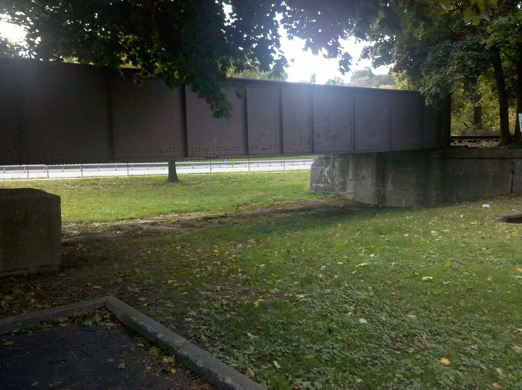 Ancien tablier de pont métallique entre des appuis de maçonnerie.