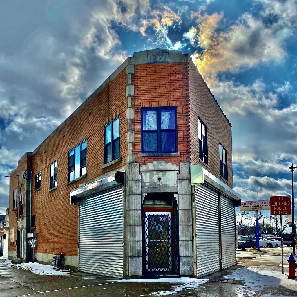 Former brick corner shop with closed metal shutters.