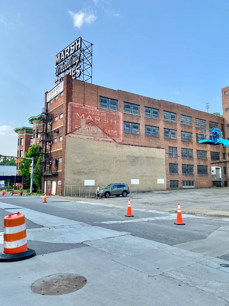 Brick façade of the former Marsh factory with its rooftop sign.
