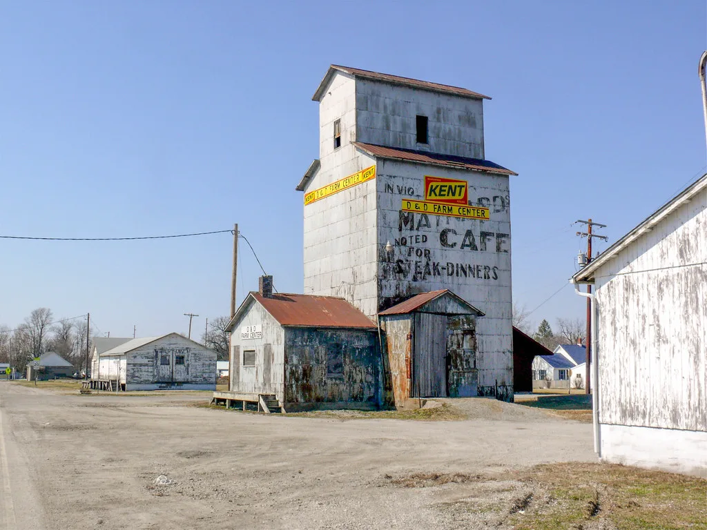 Old grain elevator with peeling cladding and small rusty-roofed annexes.