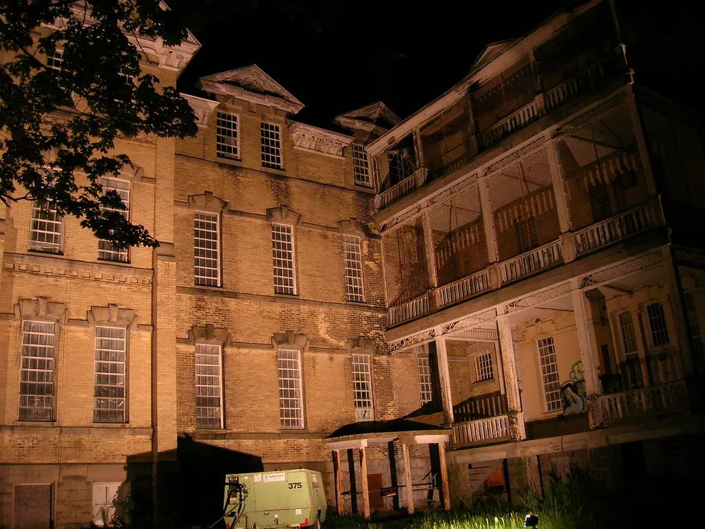 Night view of an old brick building with decayed wooden balconies and broken windows.