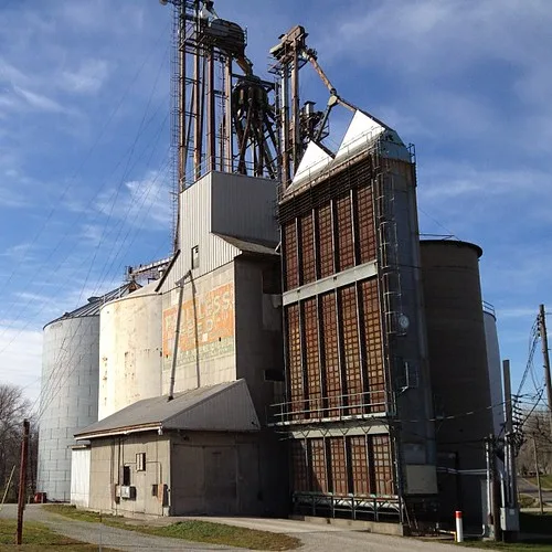Ancien élévateur à grains avec silos et structure métallique vieillie.