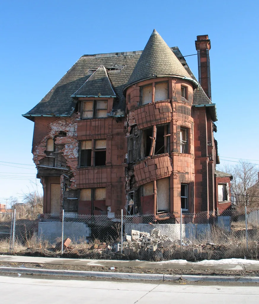Old turreted house with empty windows and a deteriorated facade.