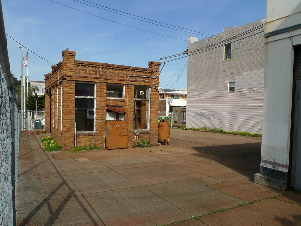 Old small brick service station with rusty pumps.
