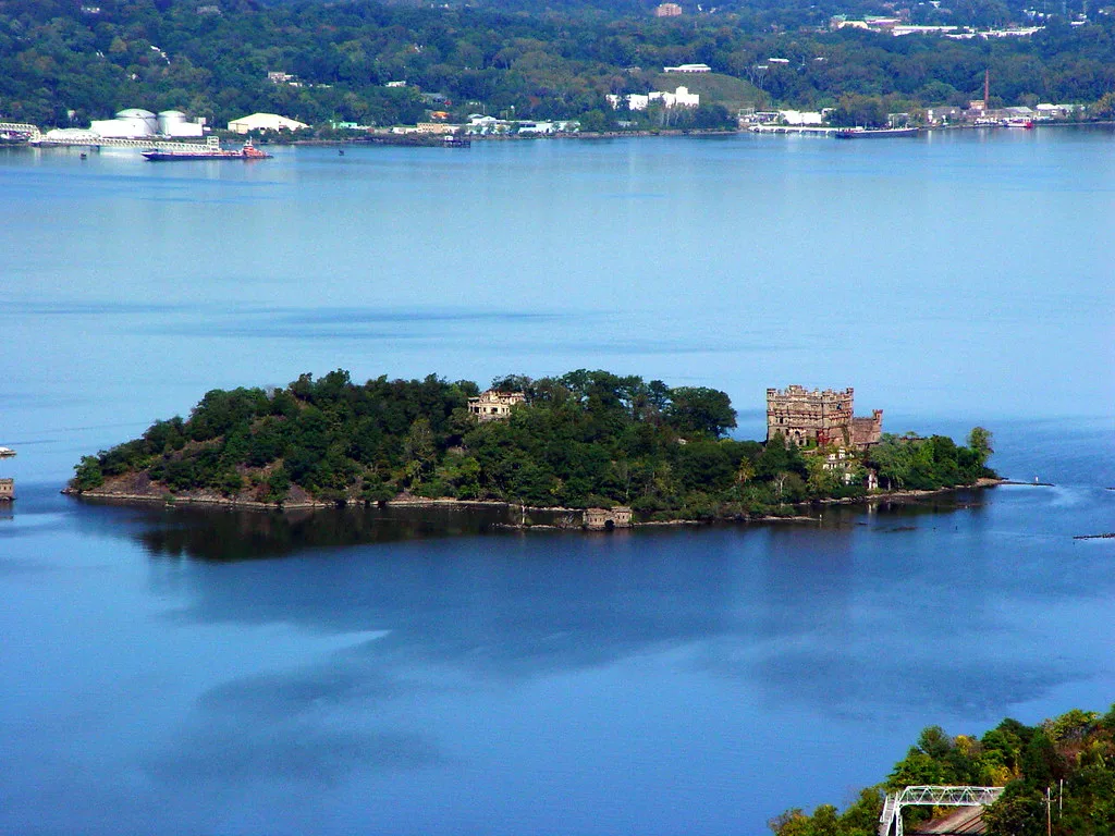 Ruines de bâtiments sur une île boisée au milieu d’un fleuve.