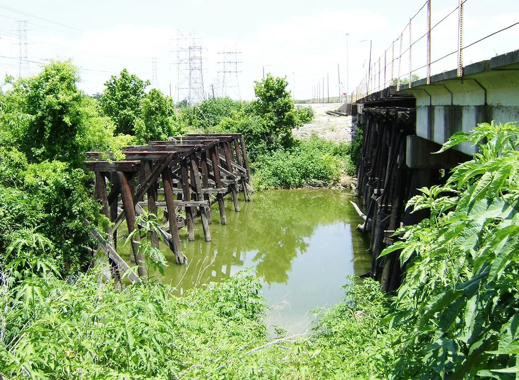 Vestiges des supports en bois d’un ancien pont près d’un pont récent.