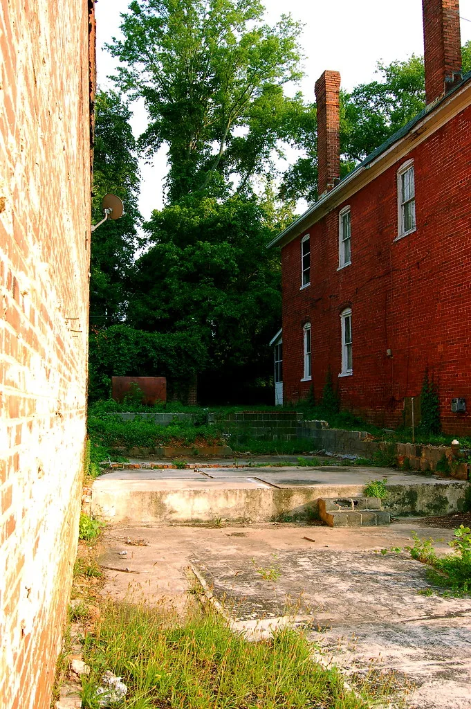 Disused slabs and foundations between two brick walls.