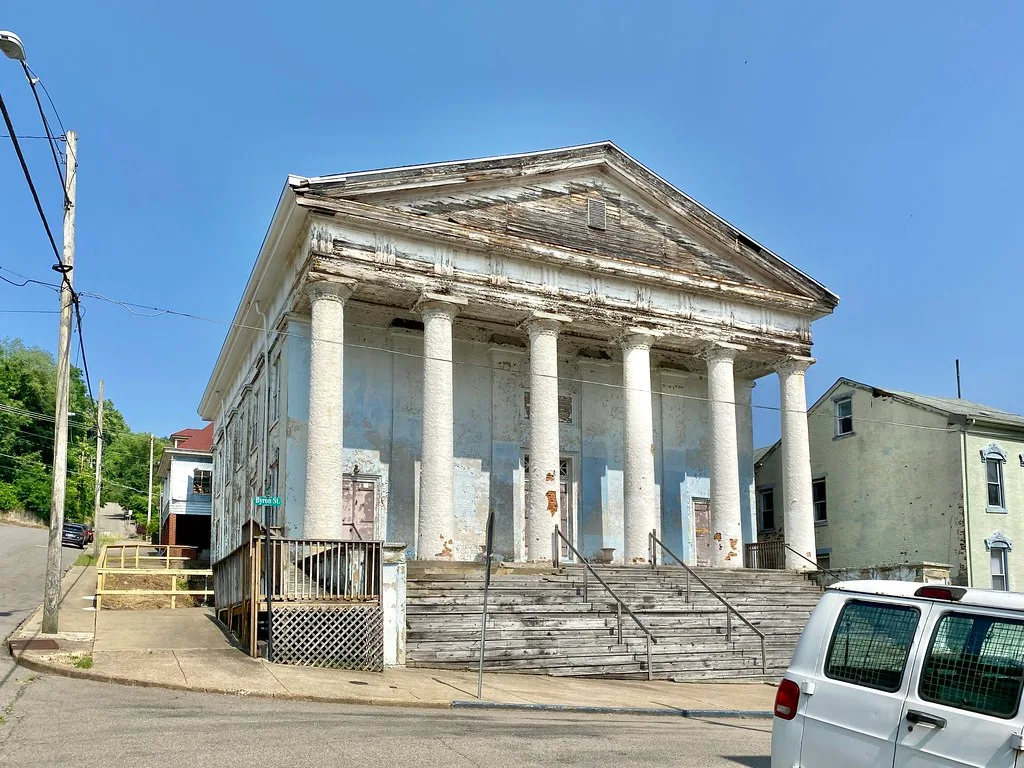 Old columned building with a heavily deteriorated pediment and facade.