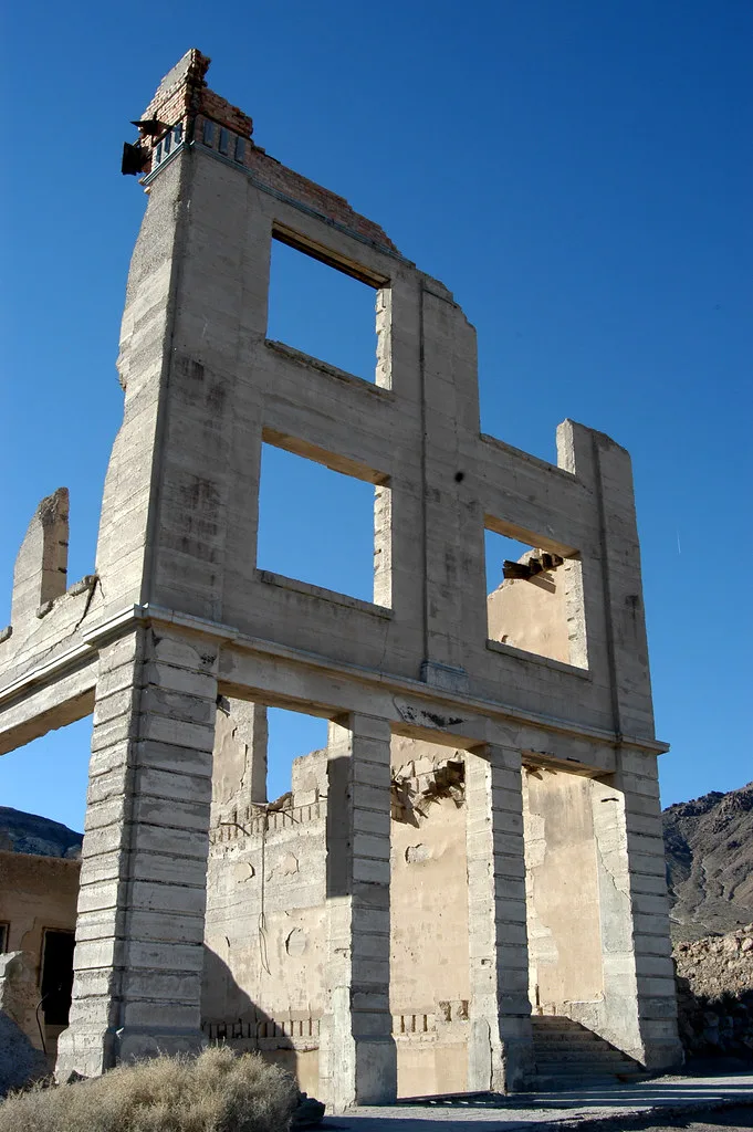 Façade de béton en ruine aux grandes ouvertures vides.