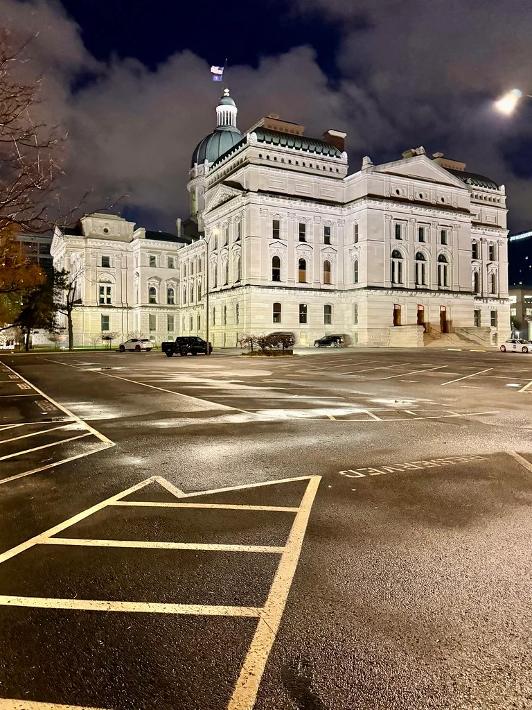 Indiana Statehouse illuminated at night, viewed from a parking lot.