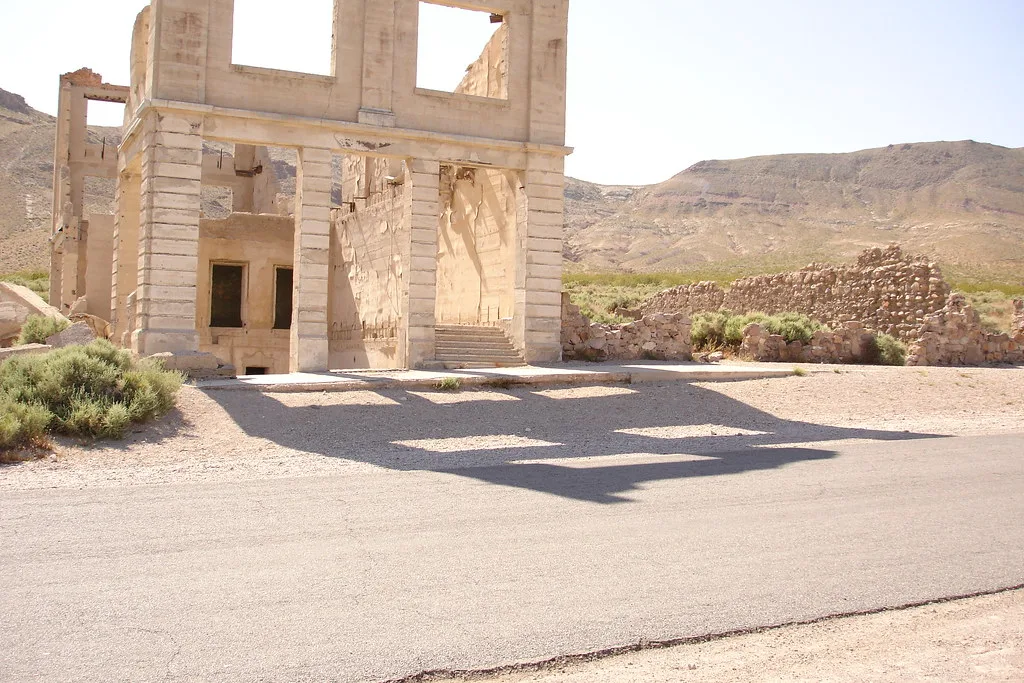 Roofless monumental facade with empty openings beneath desert hills.