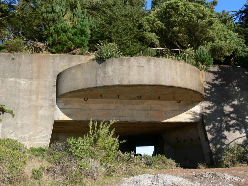 Old concrete structure with an open entrance beneath a rounded canopy.