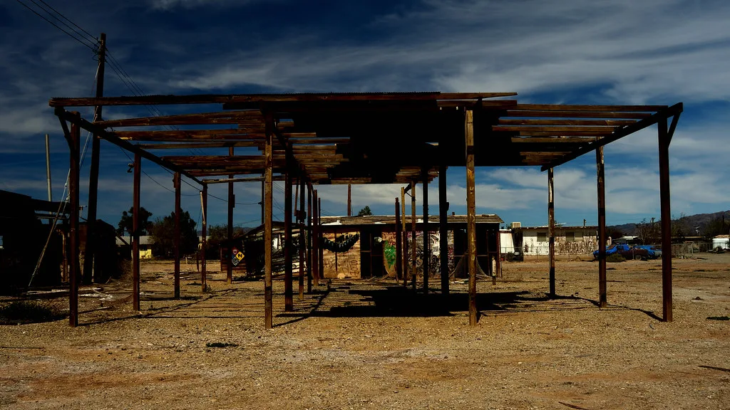 Frame of a building with a destroyed roof on arid ground.