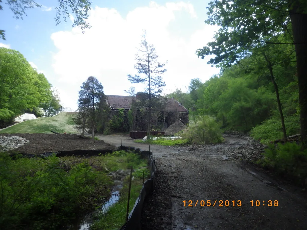 Ancien bâtiment de maçonnerie dégradé dans un vallon boisé.