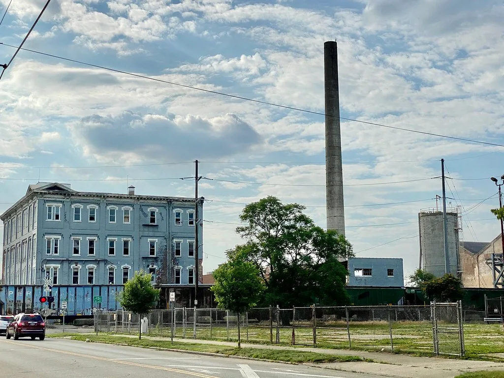 Dilapidated old industrial complex with a tall chimney and a blue building.