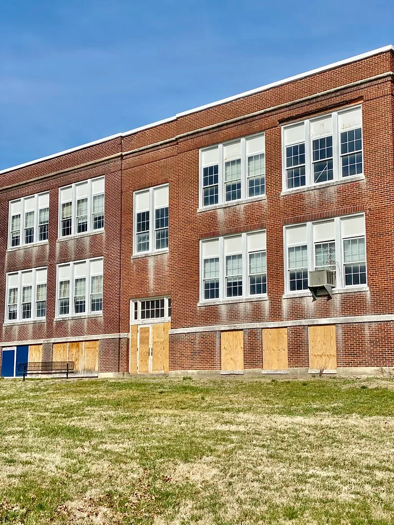 Brick building with doors and lower windows boarded up.
