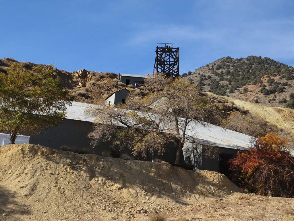 Wooden mine headframe above old buildings on a hillside.