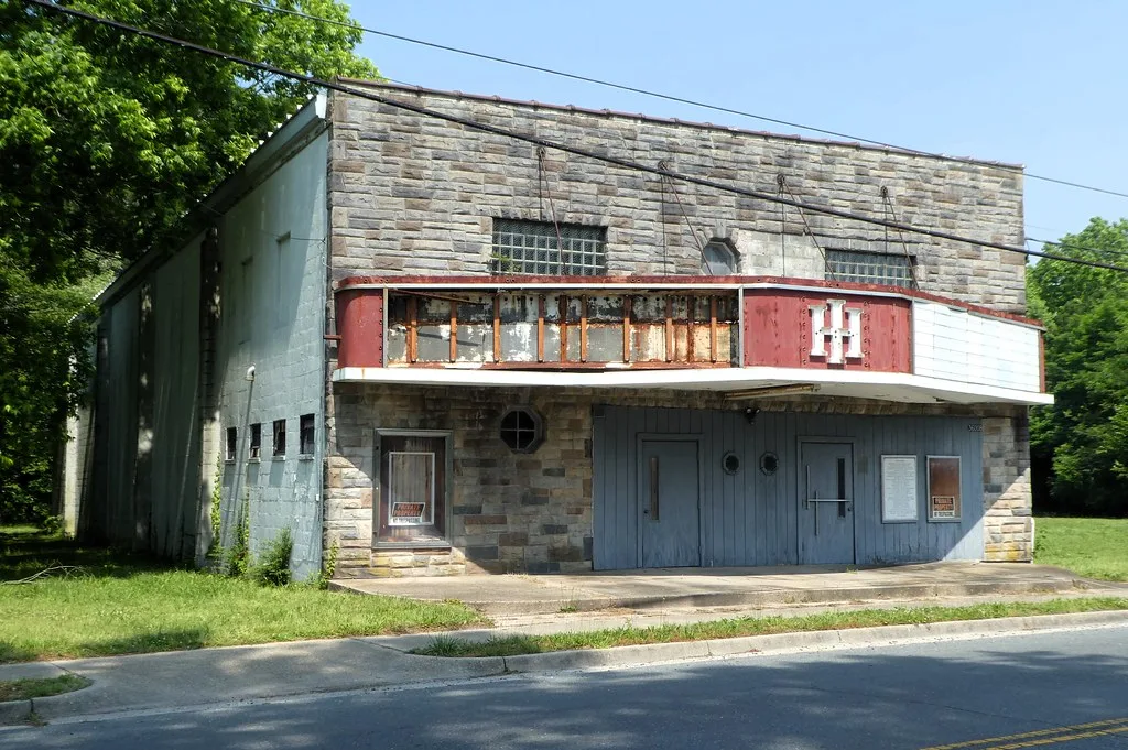 Closed old cinema with a rusty marquee and damaged sign.
