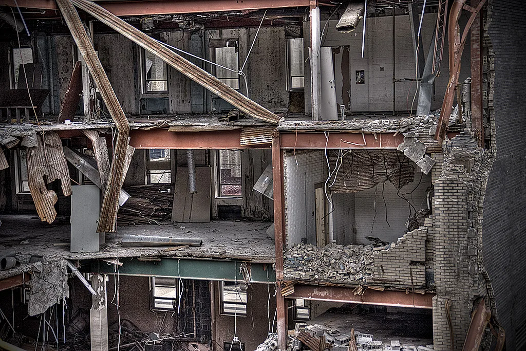 Exposed ruined floors of a building with bent beams and rubble.