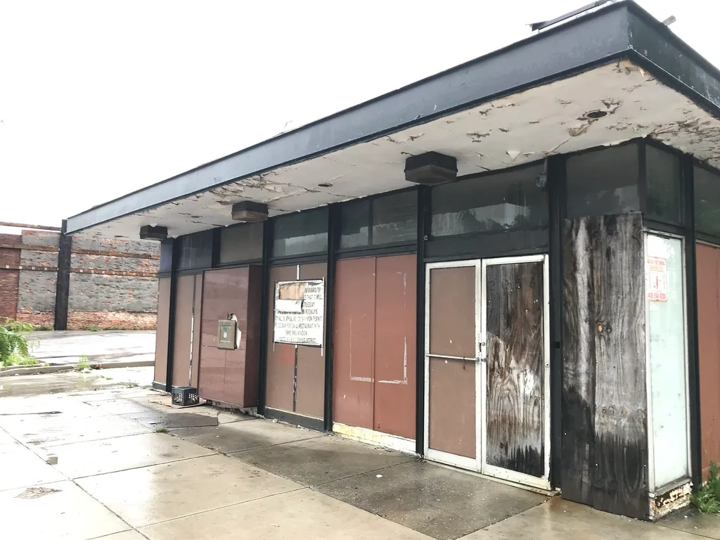 Ancien local commercial condamné aux panneaux et auvent dégradés.