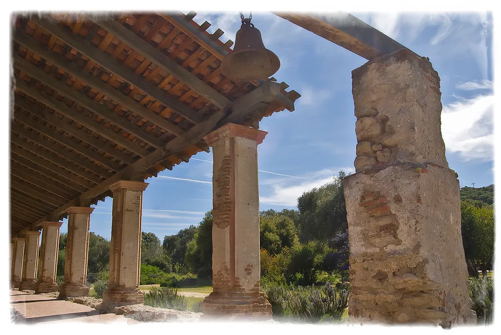 Old eroded pillars and a wall remnant beneath a wooden shelter.