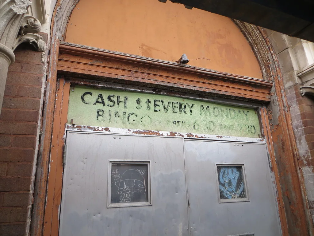 Abandoned entrance with dented metal doors beneath an old bingo inscription.