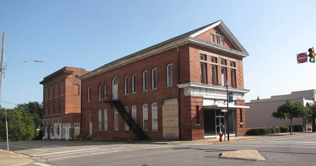 Old brick commercial building with boarded openings.