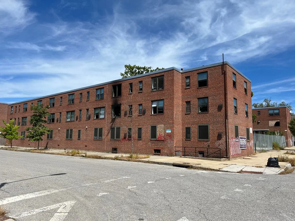 Old brick building with broken windows and fire damage.
