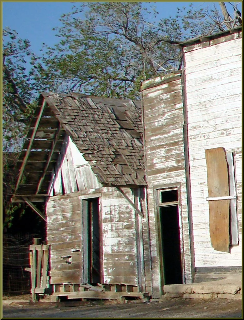 Peeling wooden facades with empty doorways and a badly deteriorated small roof.