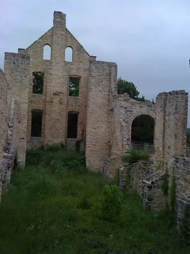 Stone ruin with tall open bays and an interior overgrown with grass.